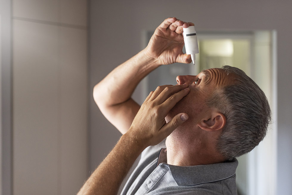 A man is using a eye drops for vision health.