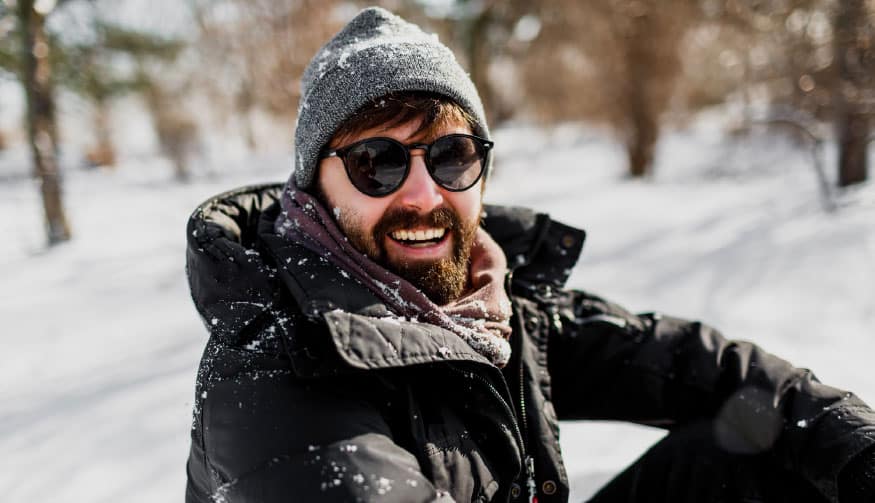 A man with sunglasses sitting in the snow.