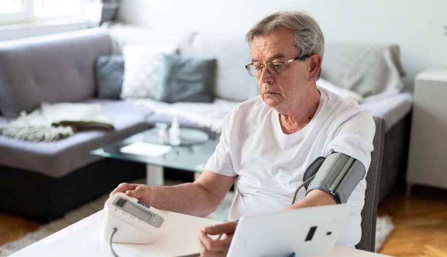 A man using a blood pressure monitor at home for eye care.