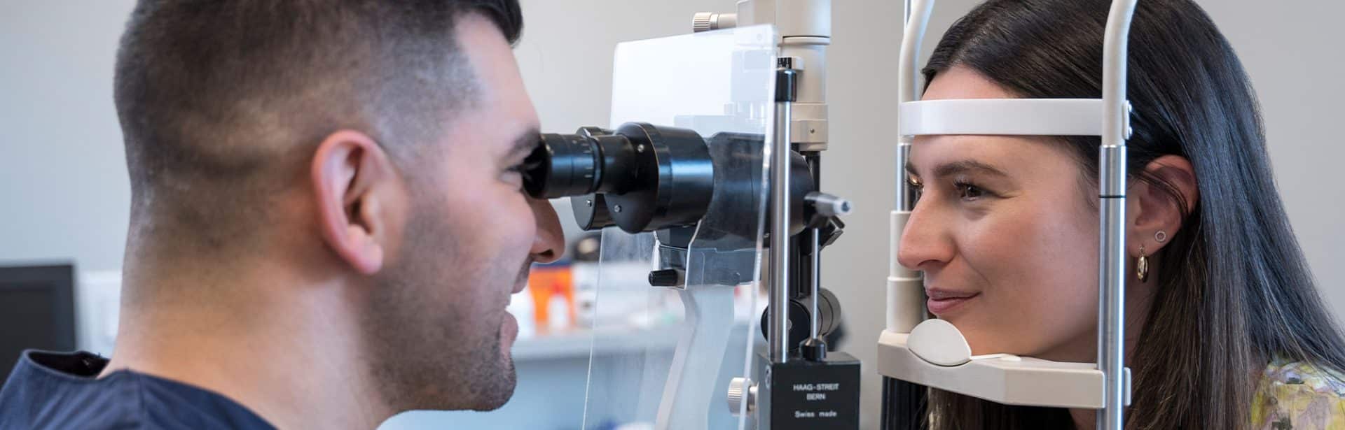 An optometrist examining a man's eye health through a microscope.