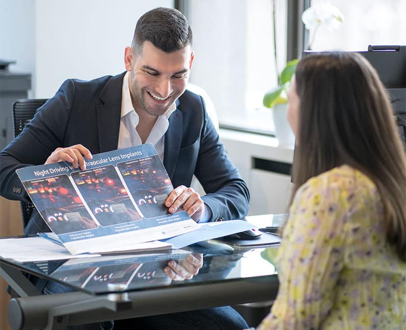 A man and woman, possibly at an eye doctor's office or optometrist, carefully examining an eye care magazine.