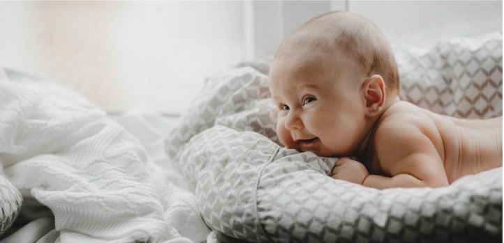 A baby laying on a blanket in front of a window, capturing the innocence and serenity of early childhood.