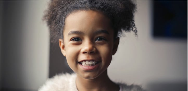 A little girl is smiling for the camera while at an appointment with her optometrist.