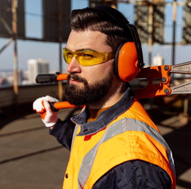 A construction worker with vision loss, holding an orange tool on a construction site.