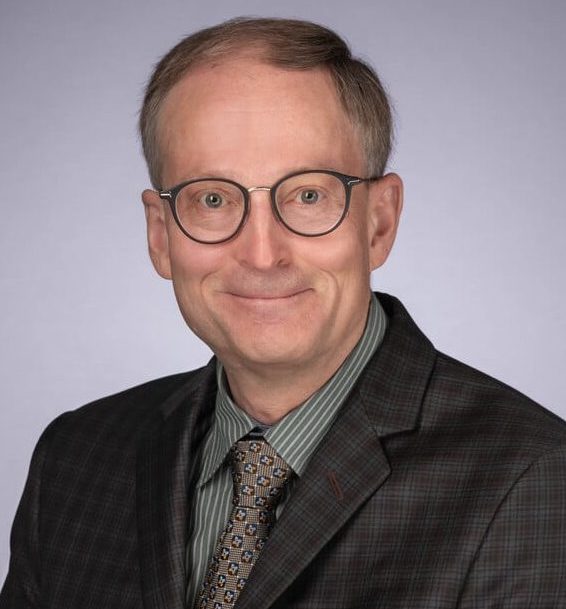 An ophthalmologist in glasses wearing a suit and tie, providing eye care.